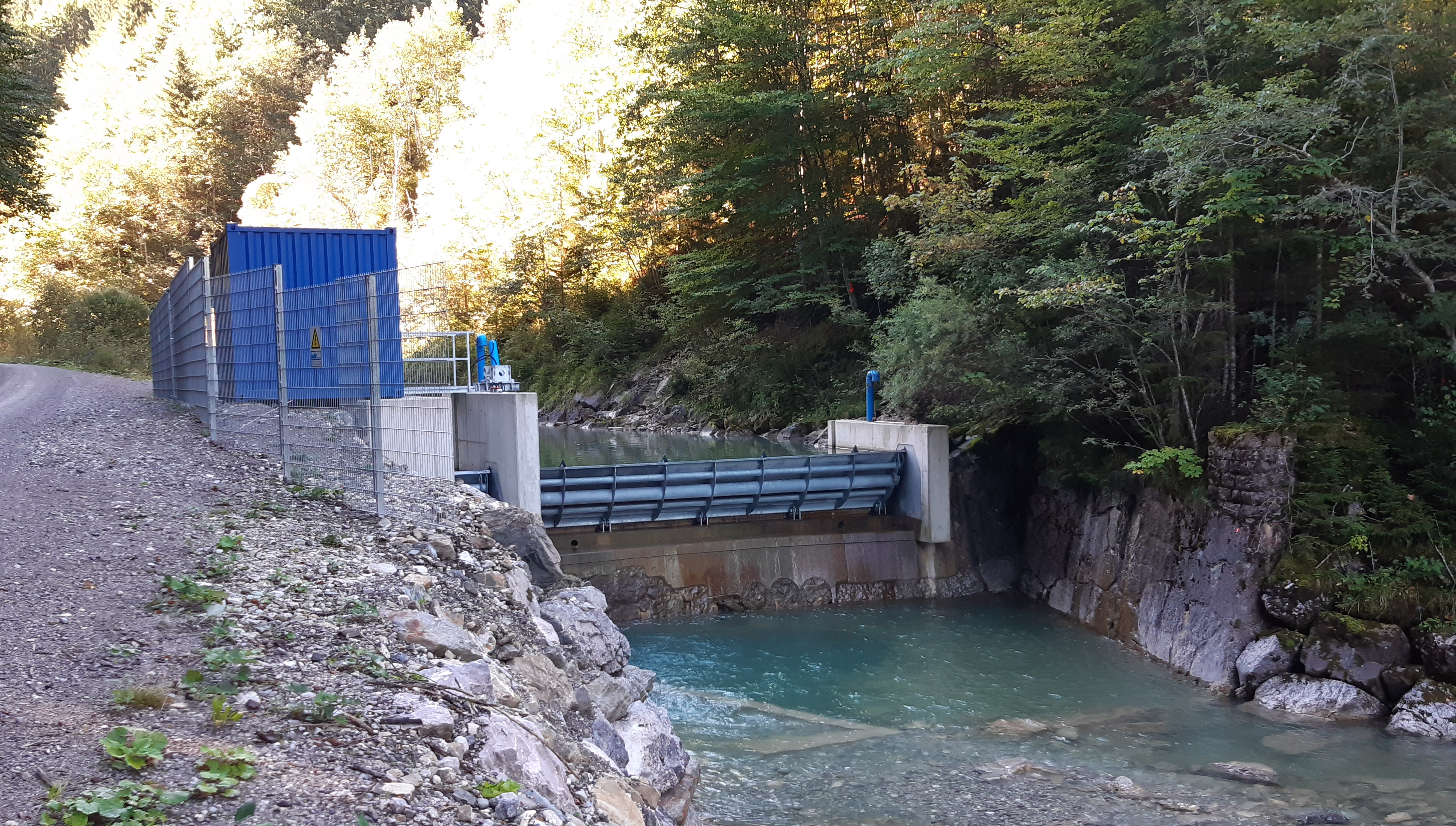 Wasserkraftwerk umgeben von Bäumen.